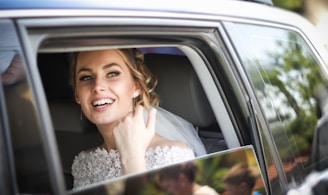 woman wearing wedding dress smiling inside car