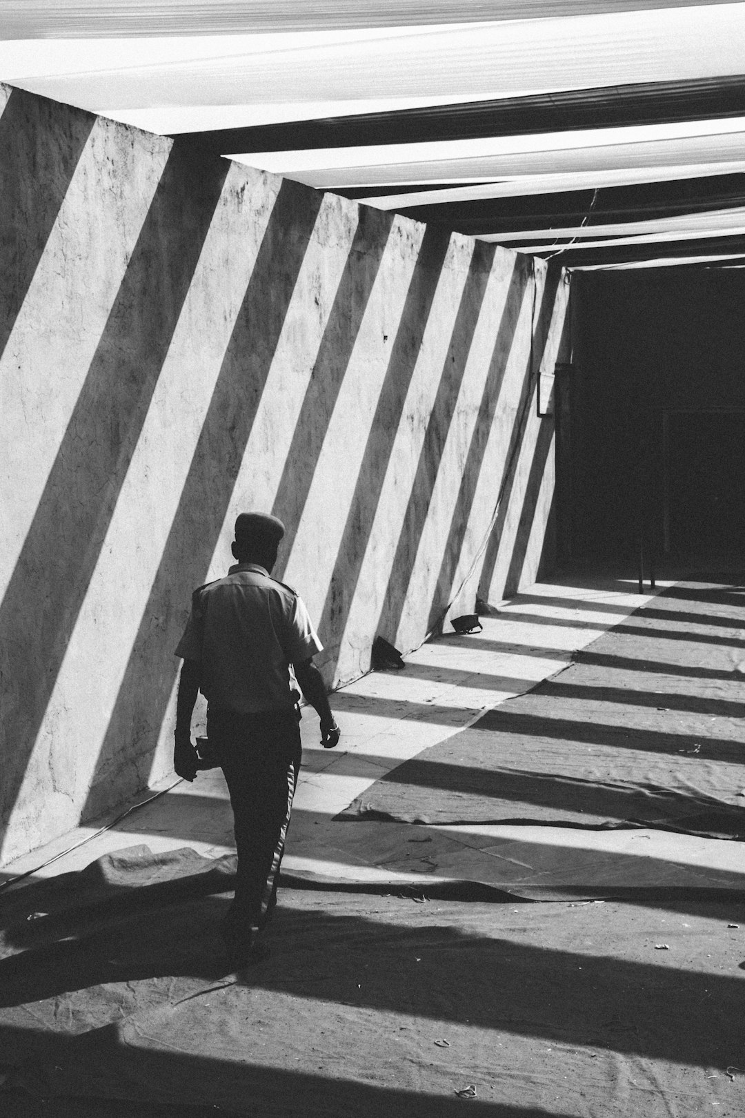 grayscale photo of man walking towards gate