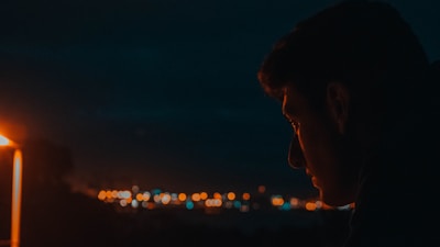 An alluring silhouette of a woman framed by the glow of city lights at dusk.