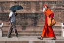 man walking beside man holding umbrella