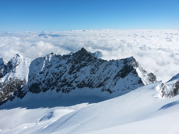 Snow-capped peaks towering above a crystal-clear alpine lake under a bright blue sky.