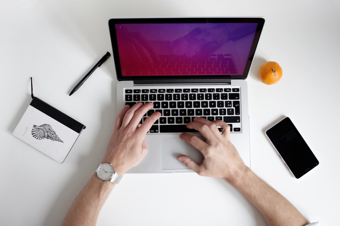 Laptop on white table with someone typing on keyboard