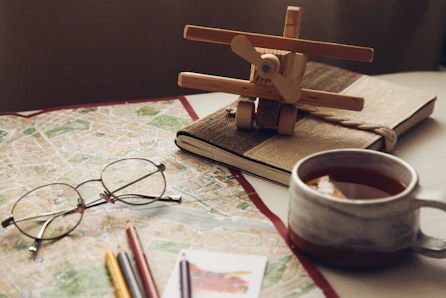 A cozy workspace with paper maps, handwritten notes, and a warm cup of tea on an ivory desk.