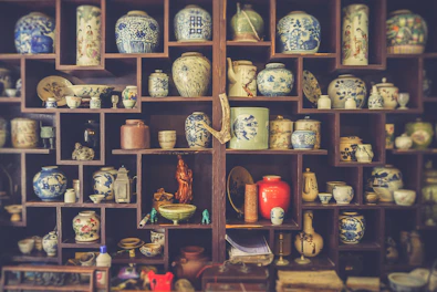 A vintage Chinese-style vase with intricate patterns and rich colors displayed on a classic wooden shelf.