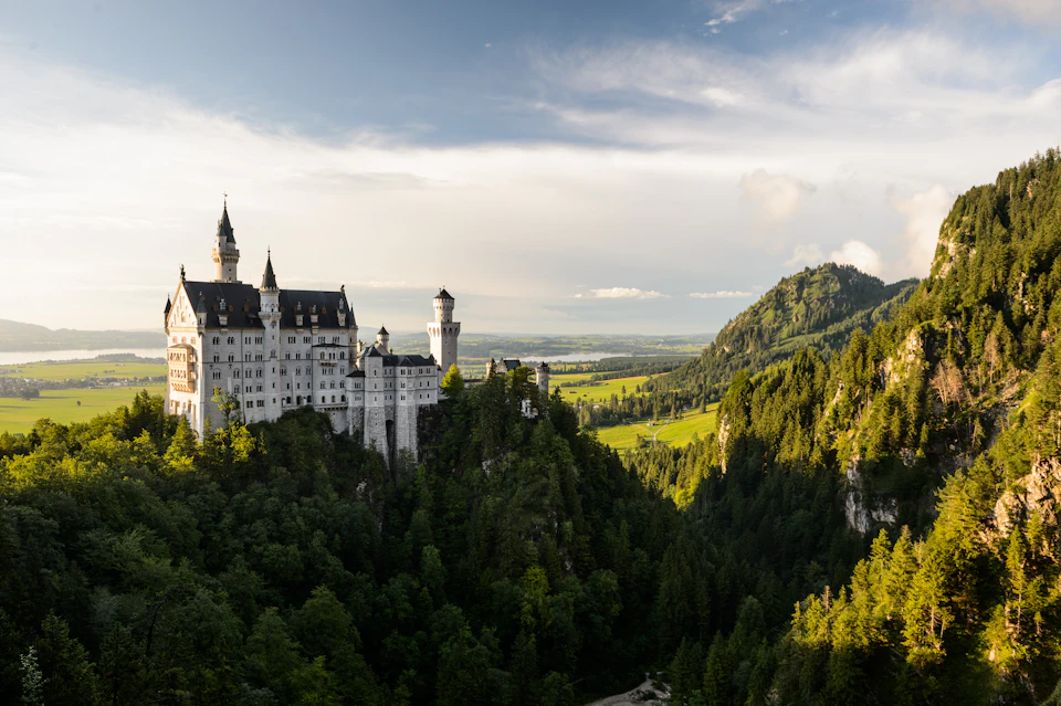 Majestic white stone castle perched on a cliff overlooking a lush valley landscape