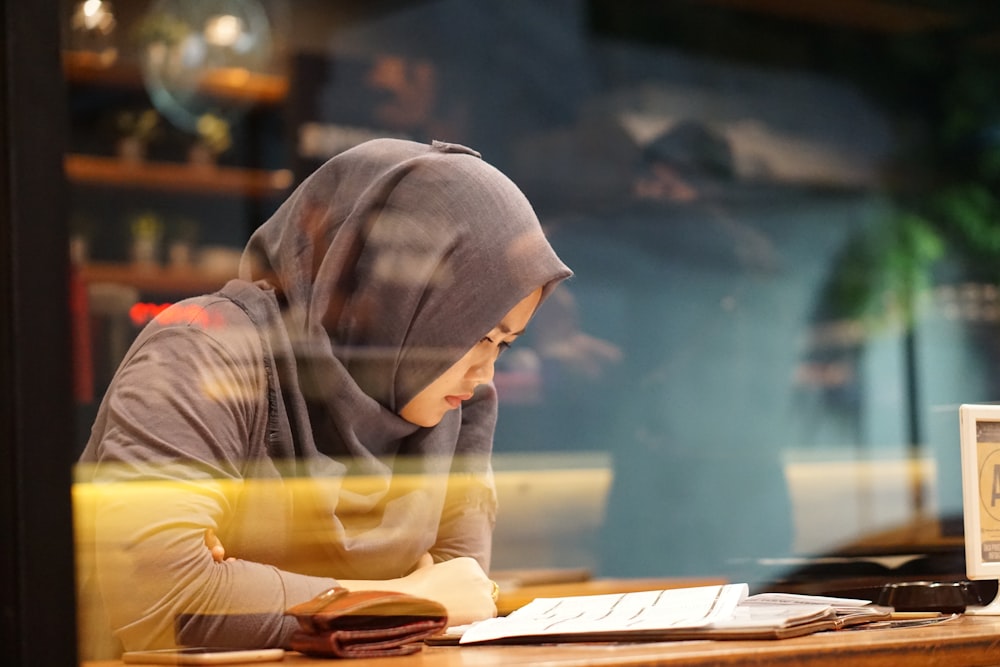 woman in gray traditional dress reading book