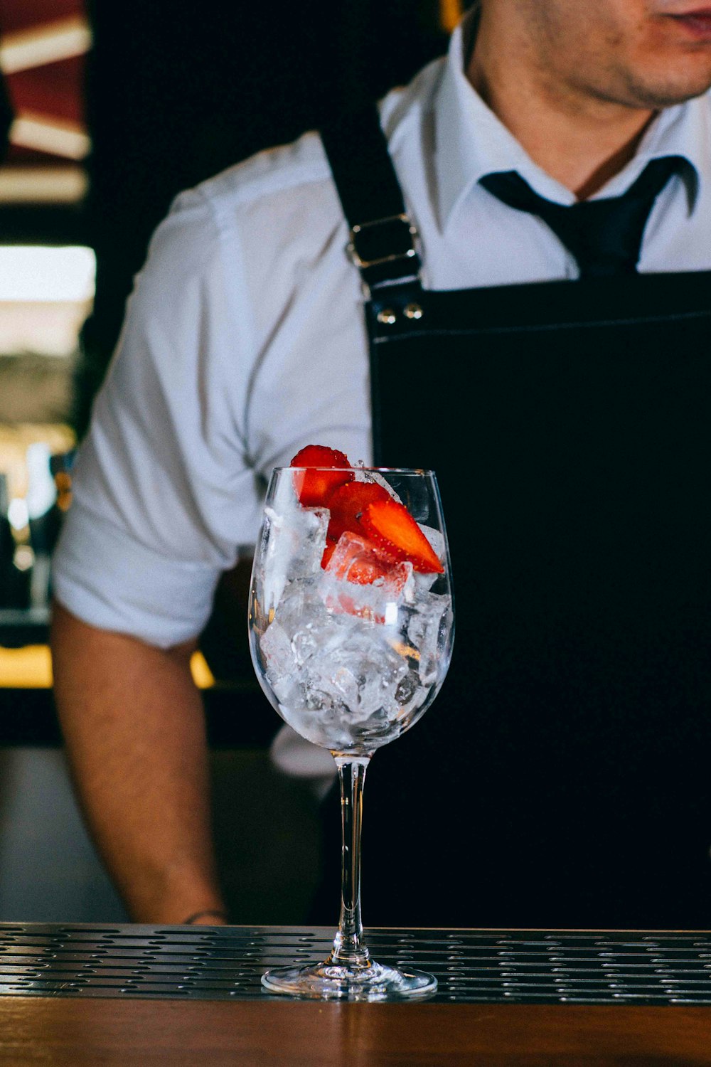 man wearing black apron near wine glass