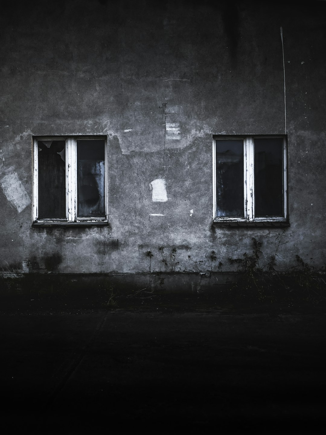 grayscale photo of concrete house with two windows