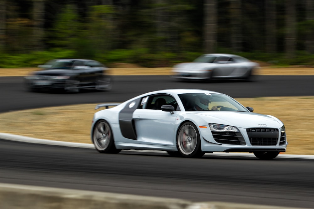 Audi R8 blanco conduciendo por carretera gris