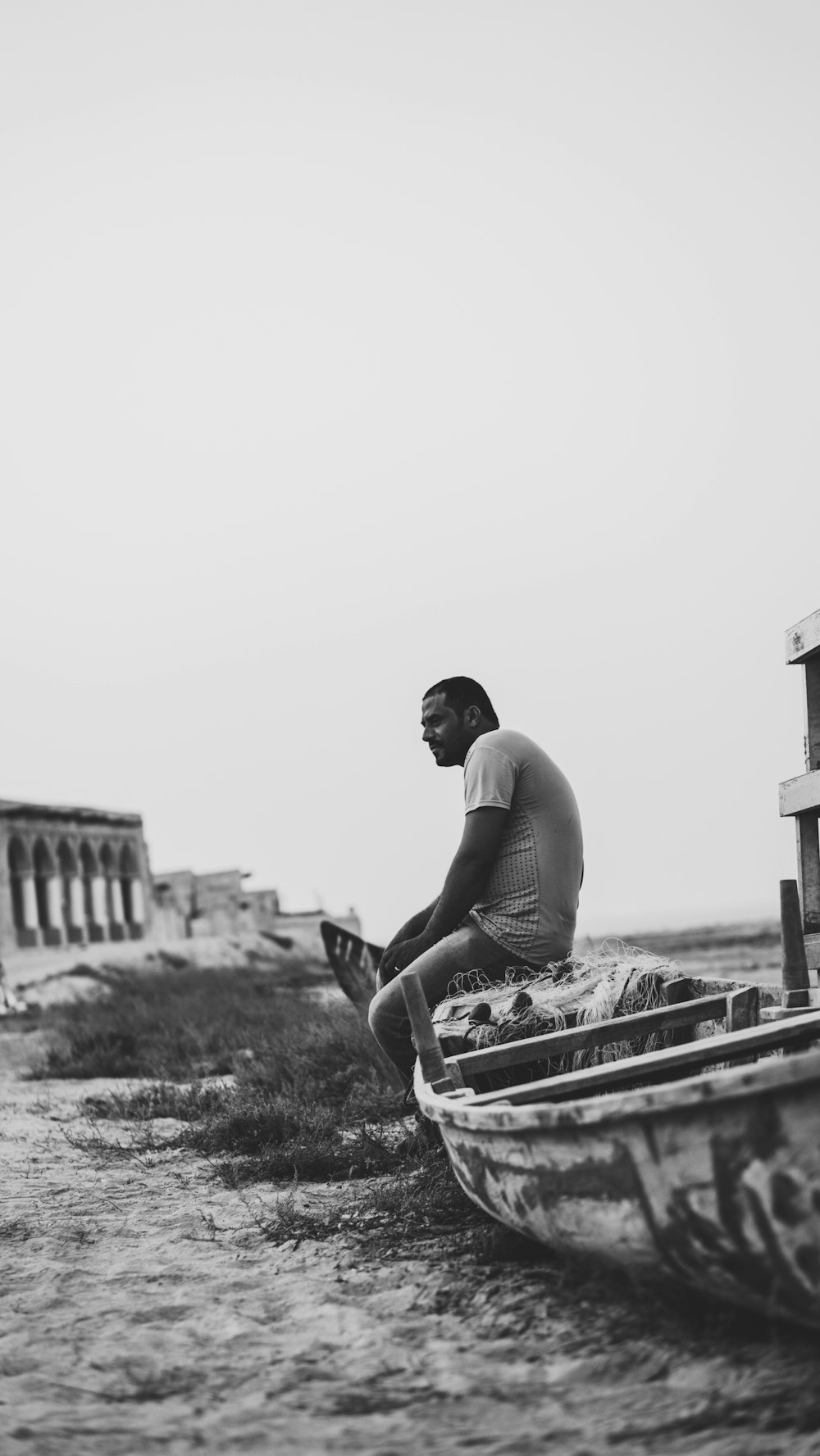 grayscale photo of man sitting on canoe