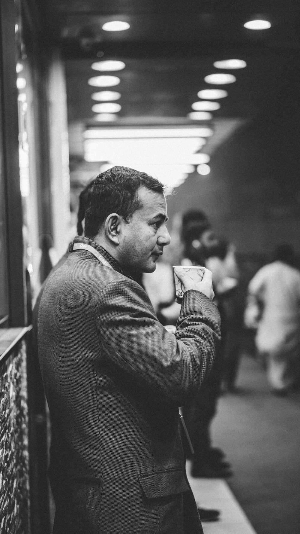 grayscale photo of man drinking on plastic cup