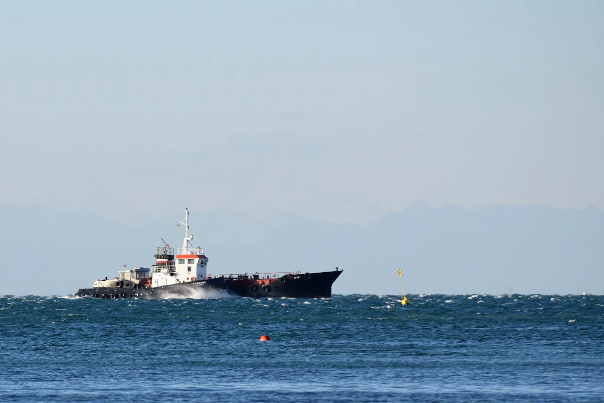 A sleek cargo ship cutting through ocean waves under a bright sky, symbolizing speed and reliability.
