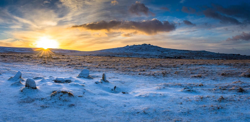 snow covered ground with mountain background during golden hour