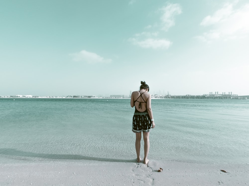 woman in black outfit standing on beach sand