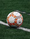 red and orange soccer ball on green grass field