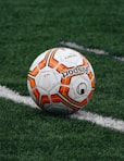 red and orange soccer ball on green grass field