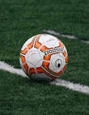 red and orange soccer ball on green grass field