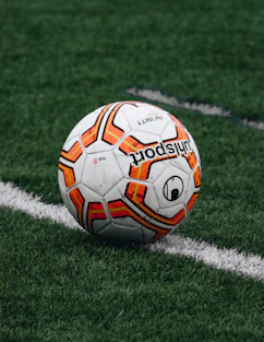 red and orange soccer ball on green grass field