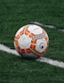red and orange soccer ball on green grass field