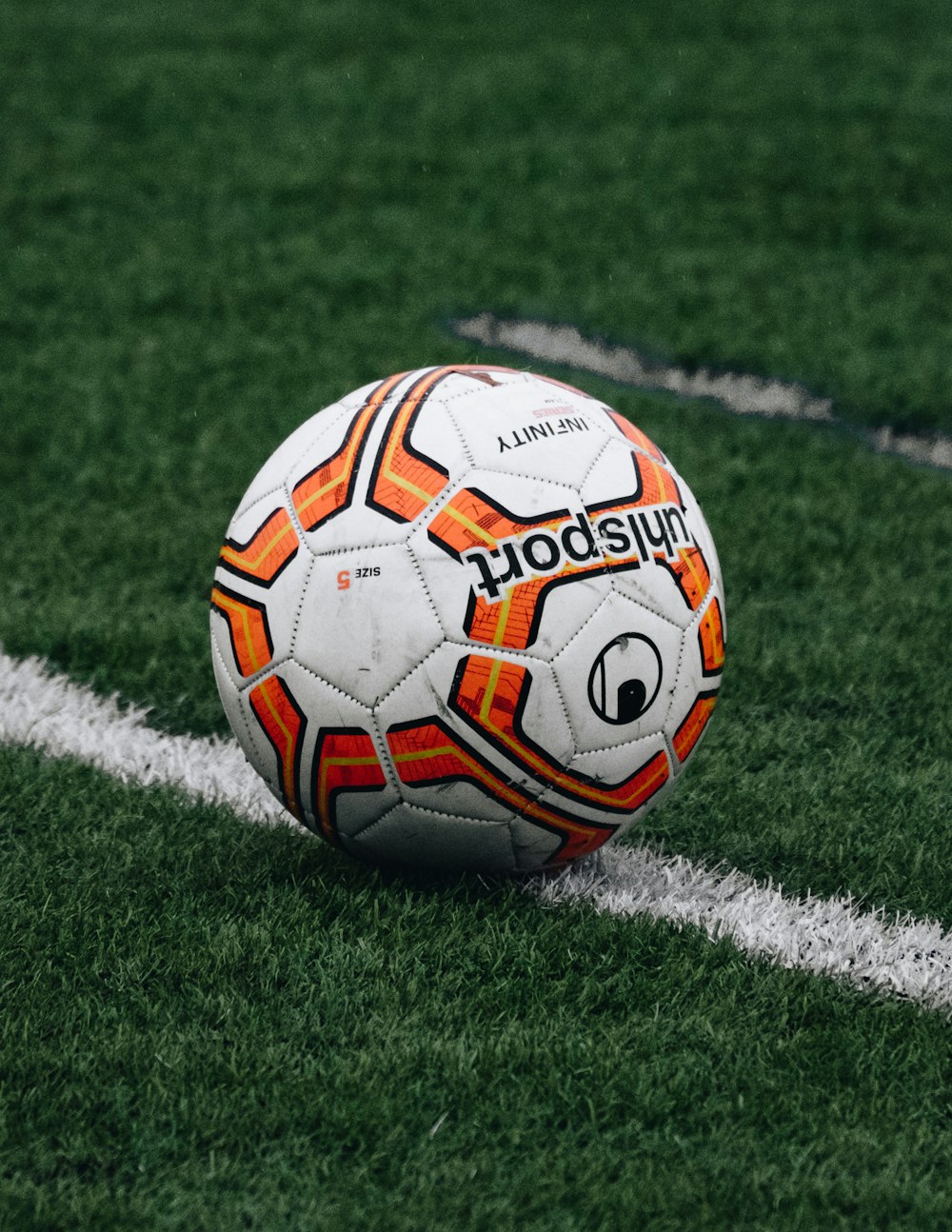 Balón de fútbol rojo y naranja en campo de hierba verde