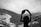 person wearing hooded jacket standing while looking at the snow-covered mountain during daytime
