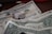 A close-up view of several US dollar bills and coins arranged on a surface. The image prominently features one-dollar bills and several quarters. The faded background indicates some currency notes are stacked slightly out of focus.