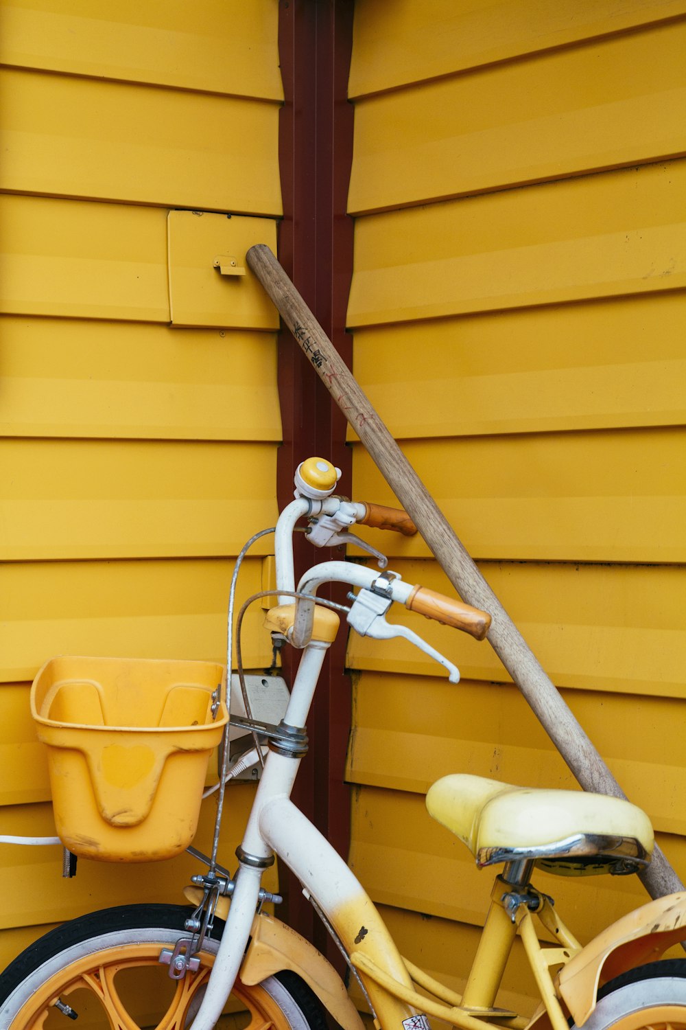 Bicicleta blanca y amarilla junto a poste de madera marrón
