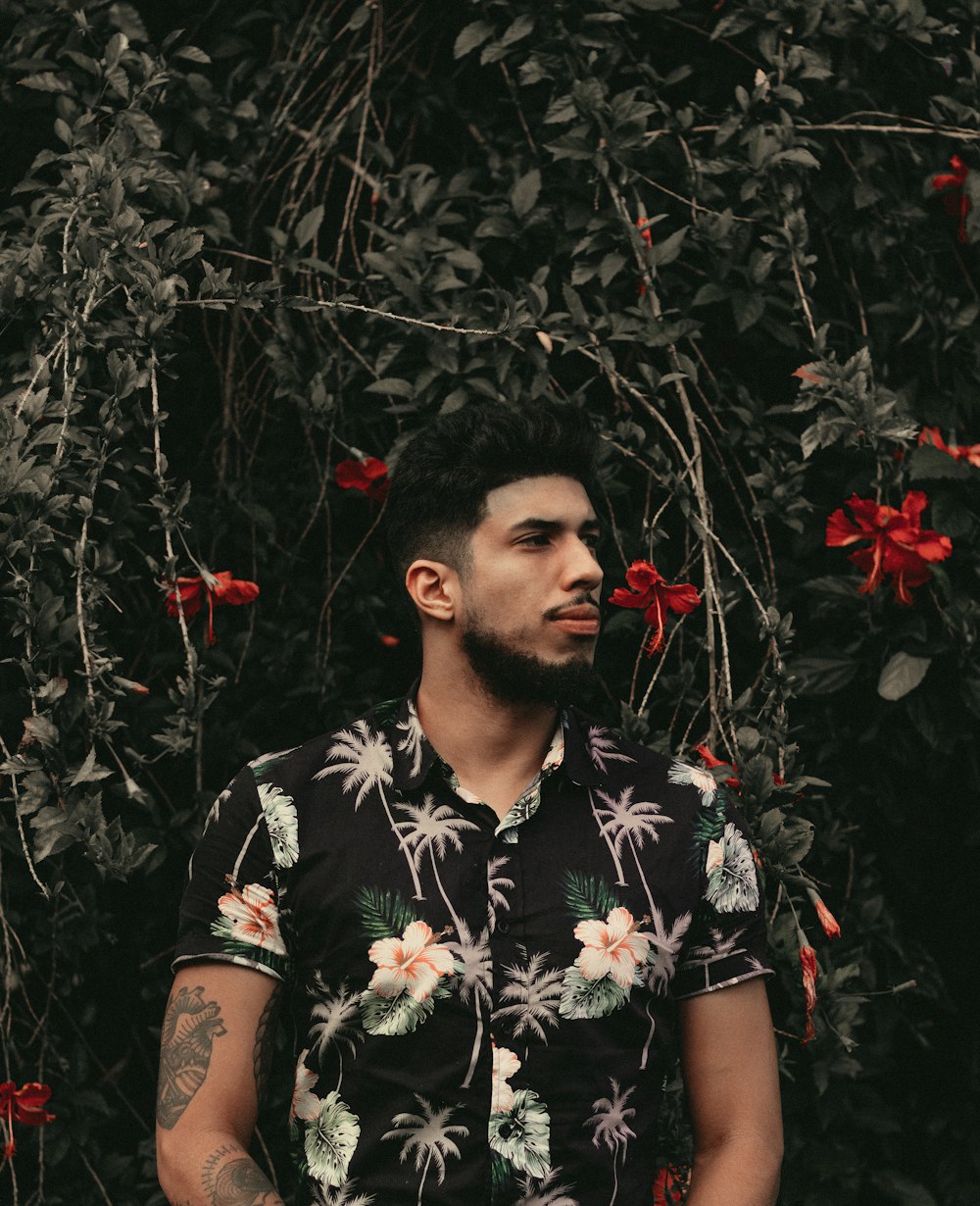 man standing in front of red flowers