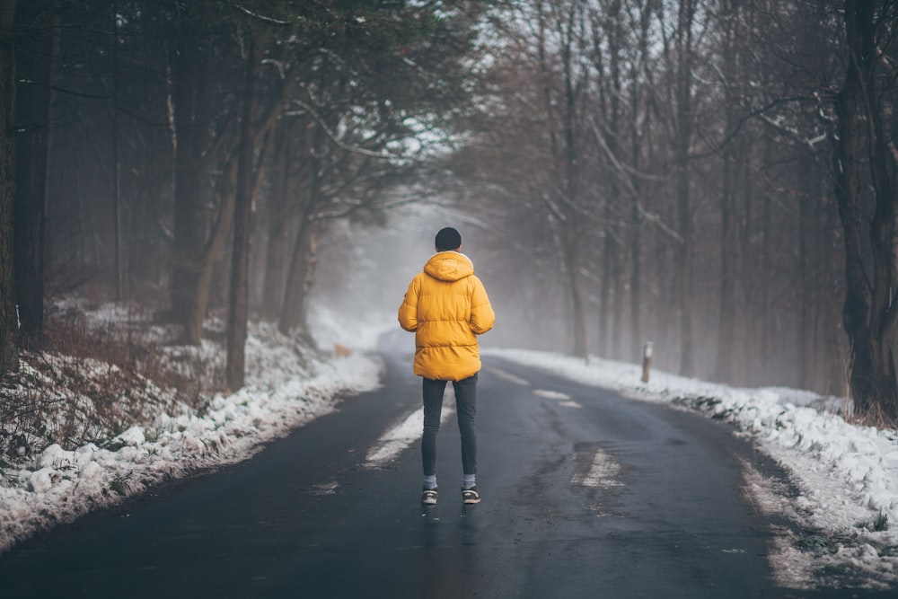 person wearing yellow jacket standing on road