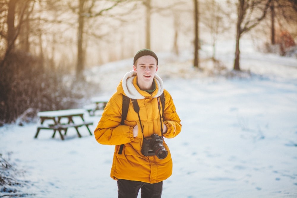 man in orange hoodie standing on near forest