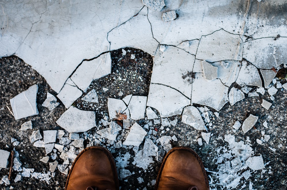 a pair of brown shoes sitting on top of a sidewalk