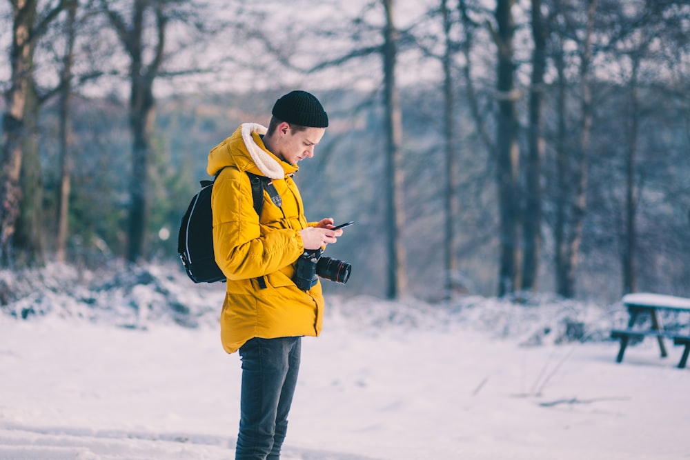 man in brown jacket using his smartphone