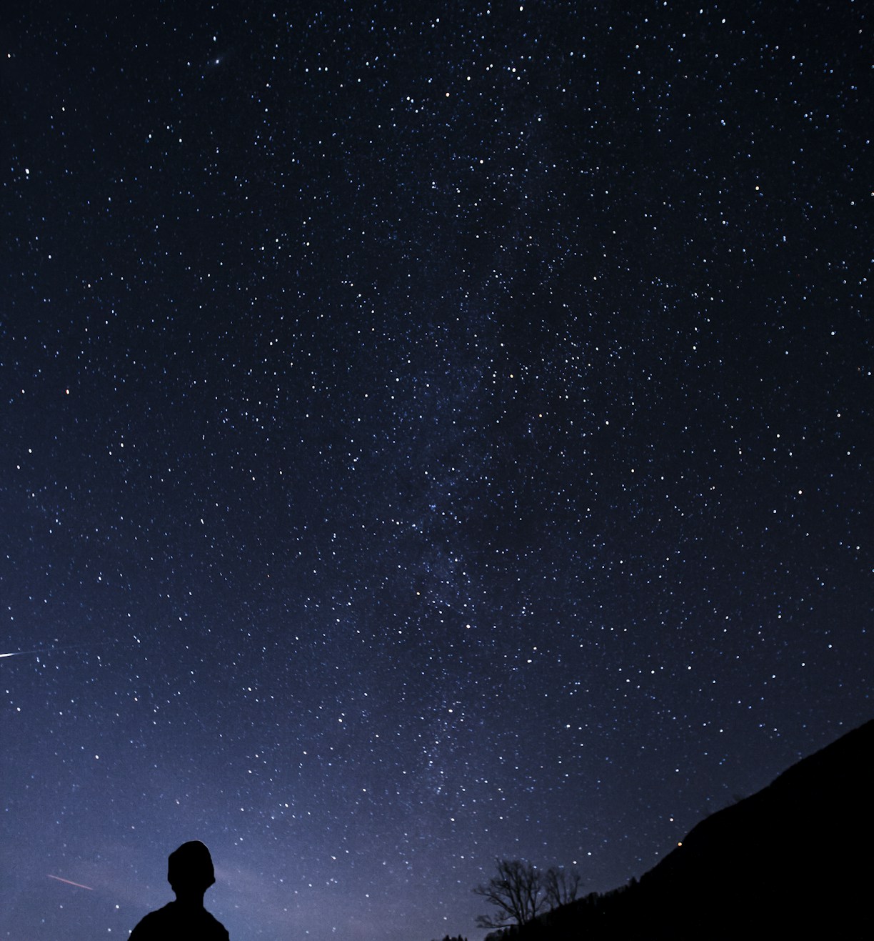 silhouette of man looking at milky way