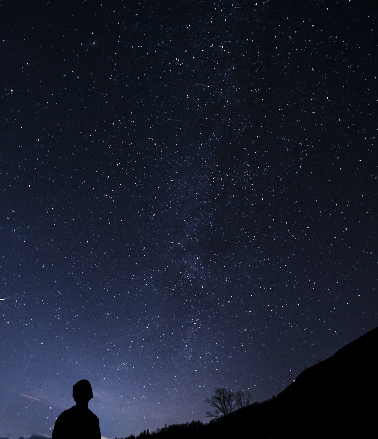 silhouette of man looking at milky way