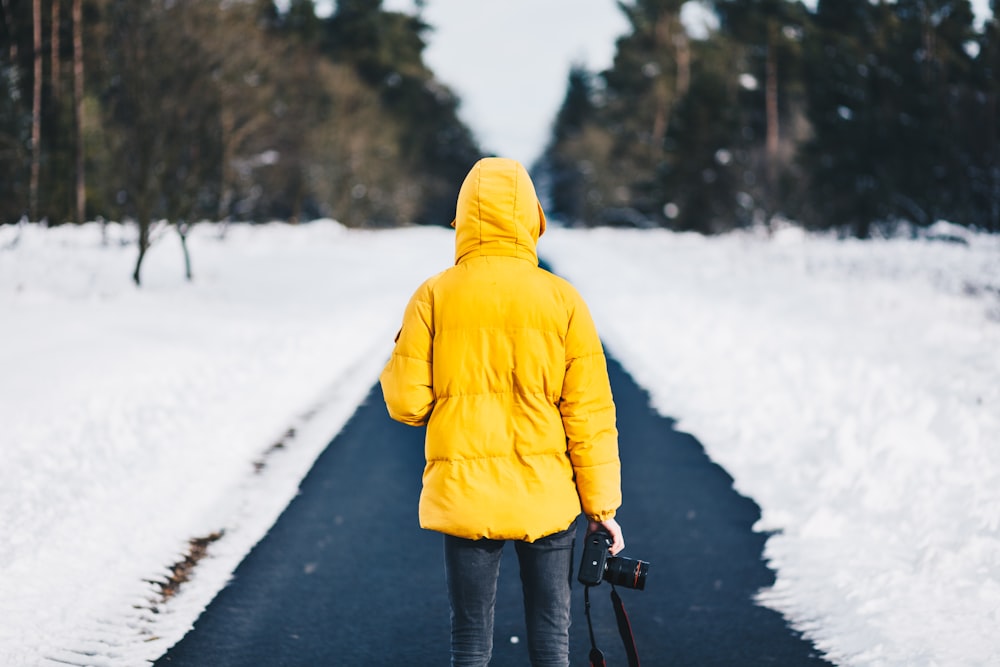pessoa na jaqueta amarela em pé entre os pisos de neve
