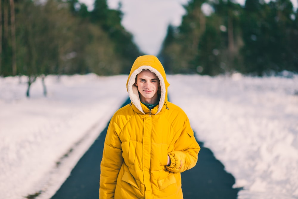 man in yellow coat walking through snow road