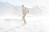 man in snowy weather holding tripod