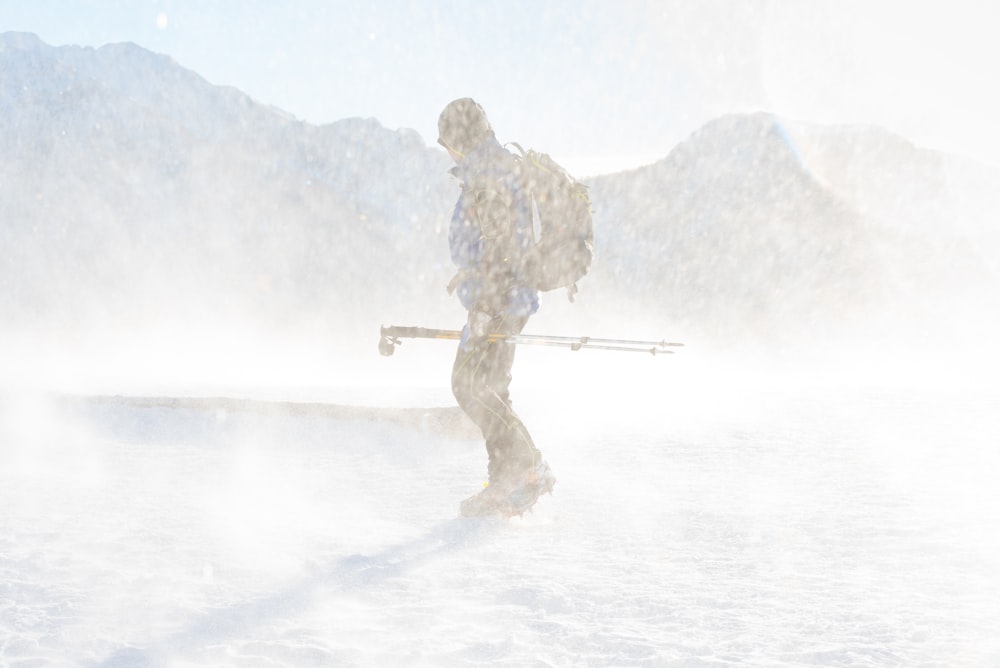 man in snowy weather holding tripod