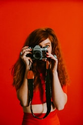 woman in red top and bottoms holding Pentax camera