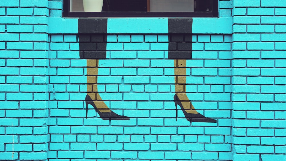 uma parede de tijolos azuis com uma janela e um par de sapatos de salto alto pintados