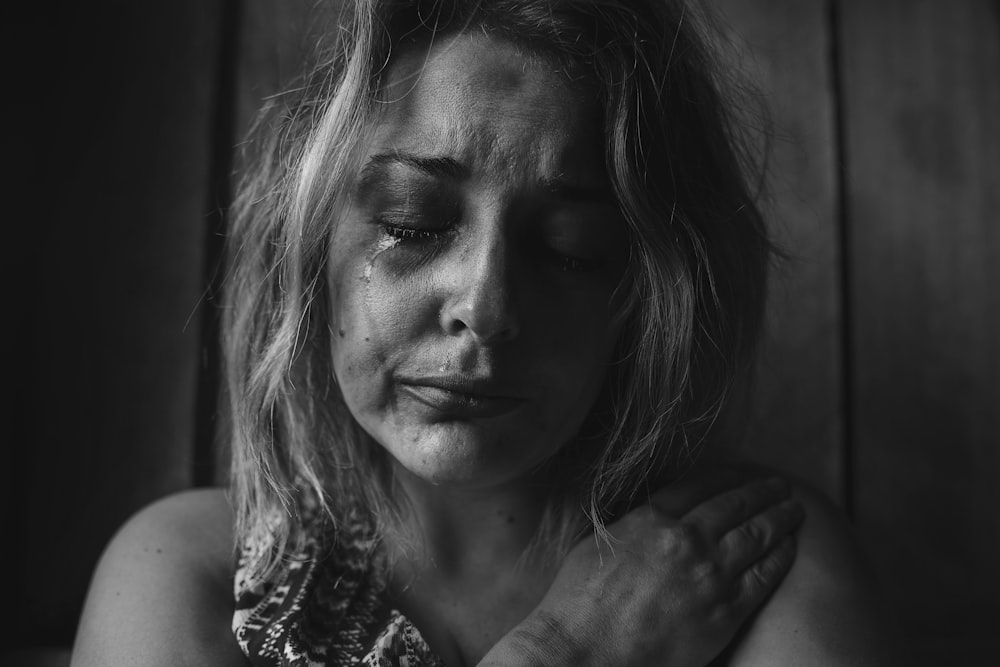 grayscale photo of woman crying holding her right chest