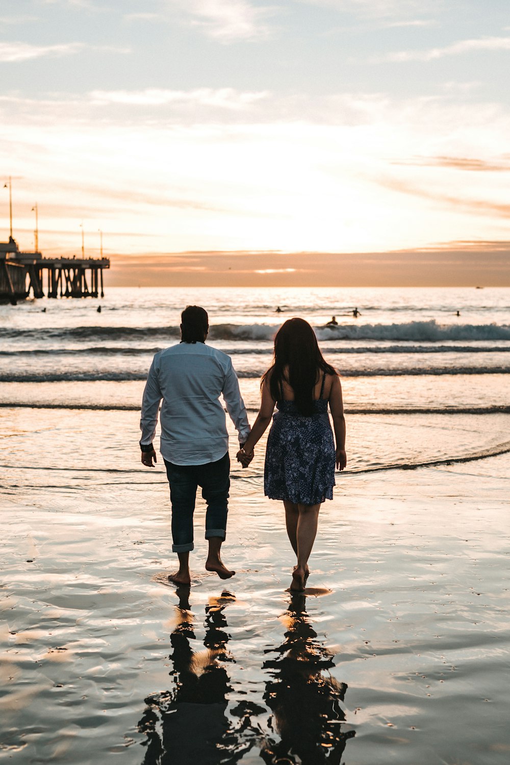 Mann und Frau halten sich an den Händen, während sie tagsüber am Meer spazieren gehen