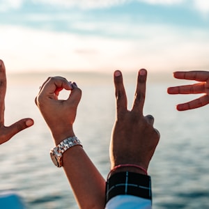 two persons forming love fingers