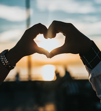 person forming heart with their hands