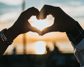 person forming heart with their hands