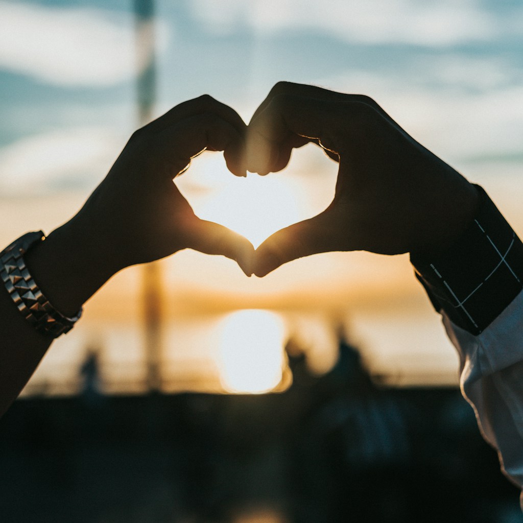 person forming heart with their hands