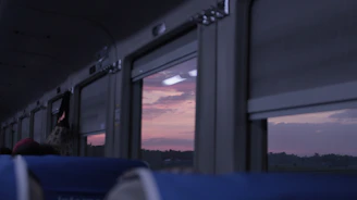 Passengers enjoying the sunset from the train deck, with mountains in the distance.