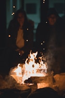 An elder sharing stories with a child around a campfire, glowing warmth between them.