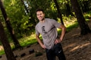 Photo of a smiling man wearing a cartoon bear t-shirt in a forest setting