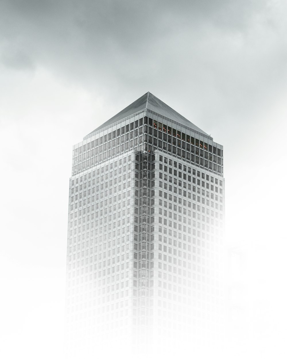 Fotografia di vista a occhio di verme dell'edificio in cemento bianco e grigio sotto il cielo nuvoloso